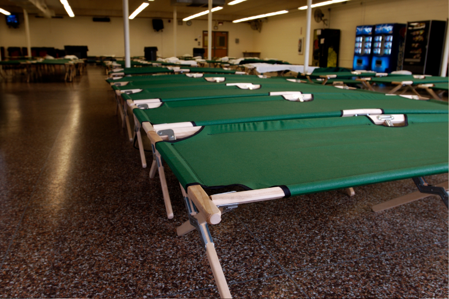 Cots set up in a shelter, points to emergency shelter information.