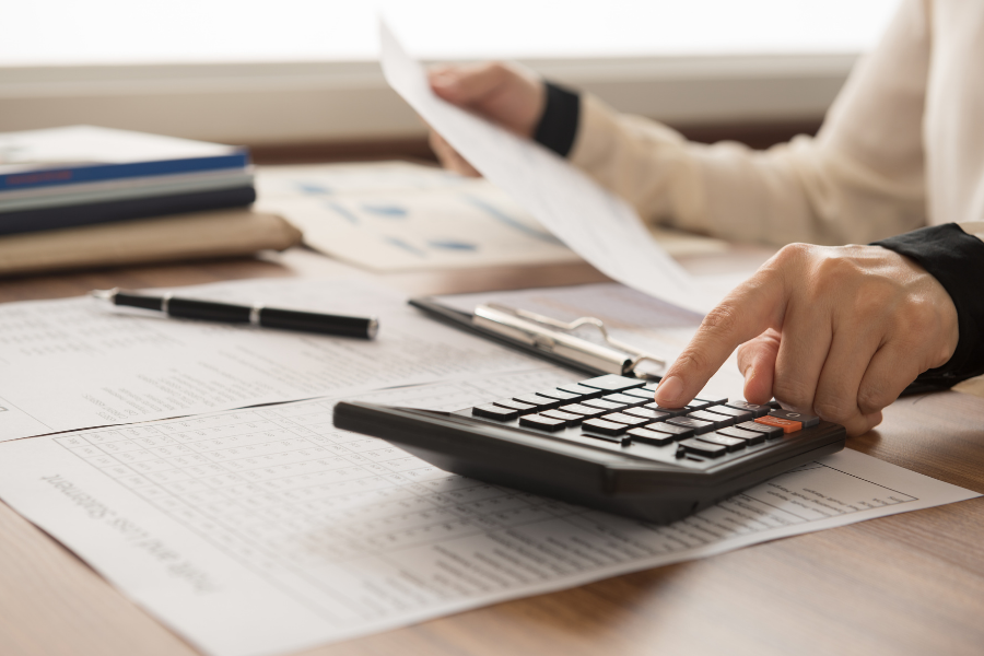 Person working on calculator with financial paperwork, points to financial literacy resources.