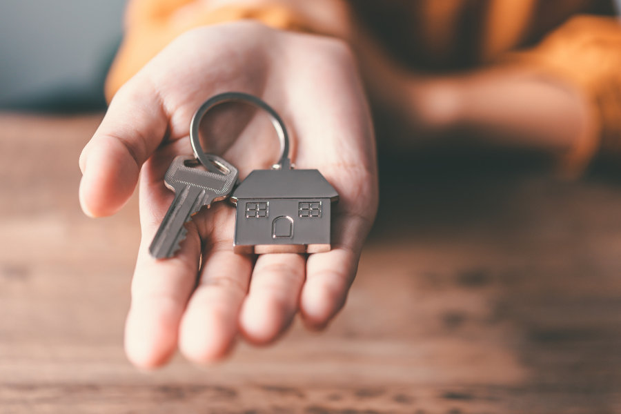 Hand holding a house key, points to housing resources.