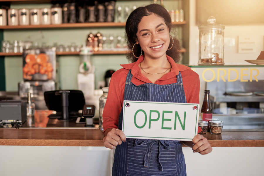 Person holding an open sign in a small business, points to small business resources.
